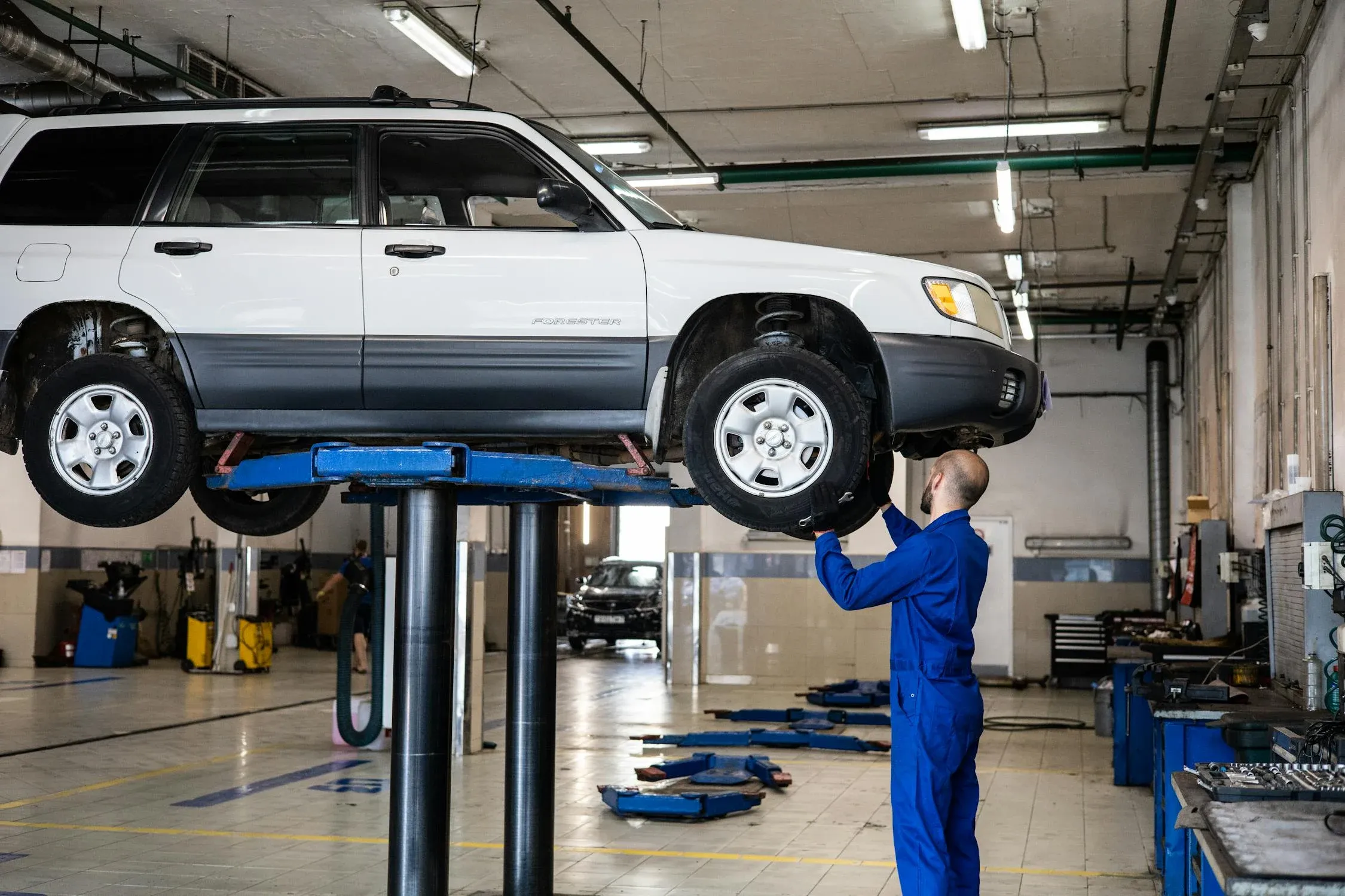 Mechanic servicing a vehicle raised in the workshop